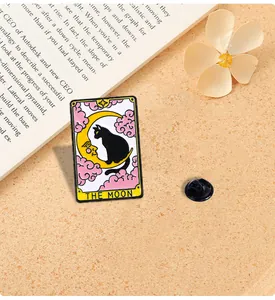 Detail of The Moon tarot cat enamel pin with alloy oil dripping on warm sand background