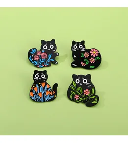 Detailed view of four black cat enamel pins with colorful floral patterns on green background