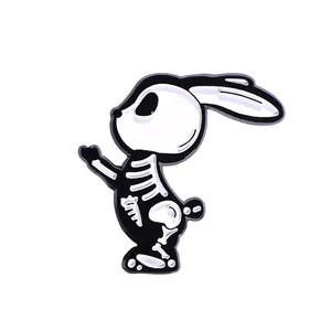 Détail d'une broche en émail noir et blanc représentant un squelette de lapin et carotte