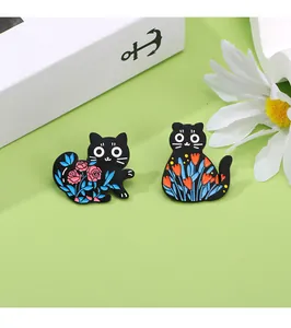 Detail of cute black cat enamel pins featuring pink rose and orange tulip floral designs