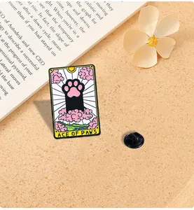 Detail of tarot style Ace of Paws cat enamel pin with black back clasp on a textured surface