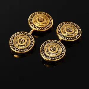 Makroaufnahme goldener Vintage Manschettenknöpfe mit Blumenmuster auf schwarzem Glas