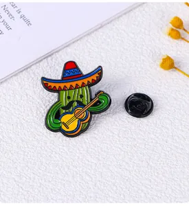 Dettaglio ravvicinato di una spilla smaltata a forma di cactus con cappello e chitarra
