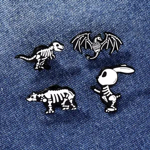 Détail de quatre épingles en émail représentant des squelettes de dinosaures sur denim