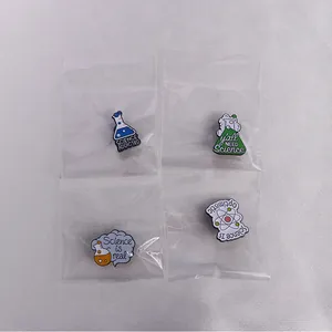 Macro shot of 4 enamel chemistry pins including flasks and atomic structures on fabric