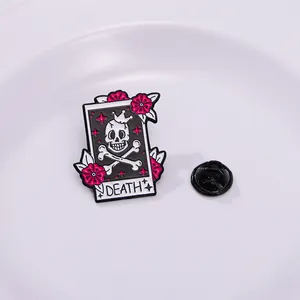 Macro detail of Death tarot card enamel pin with pink flowers on a white plate