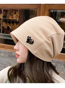 Side view of beige ribbed beanie with cute black cat floral patch on a female model