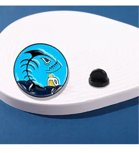 Gros plan du pin's émaillé circulaire avec motif de requin et fermoir en caoutchouc