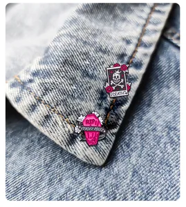 Detail of pink coffin and death tarot enamel pins on a blue denim jacket lapel