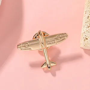 Macro shot of minimalist gold airplane brooch with a butterfly clasp on pink background