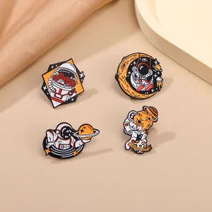Detailed close-up of four astronaut enamel pins with moon and space motifs on silk fabric