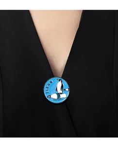 Détail d'un pin's émaillé pingouin pour la protection de l'océan sur une chemise noire