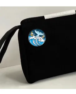 Détail du pin's émaillé baleine écologique sur un sac en toile noire avec vagues et bouteilles