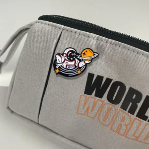 Close-up of grey canvas pencil case featuring astronaut enamel pin and WORLD print