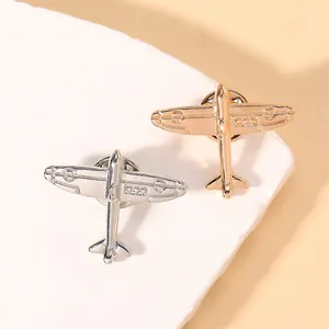 Macro detail of gold and silver airplane brooches on stone display showing metallic textures