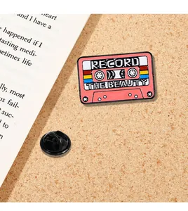 Macro detail of retro pink enamel cassette brooch featuring Record the Beauty text