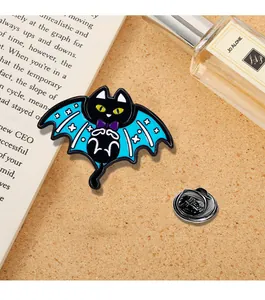 Dettaglio ravvicinato di una spilla smaltata gatto con ali blu su un libro