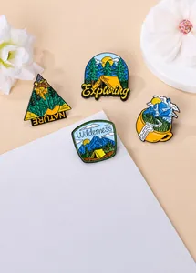 Detail of four enamel camping pins featuring forest, tents, and wilderness on beige background