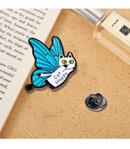 Dettaglio della spilla a gatto con ali di farfalla blu su uno sfondo di libri d'epoca