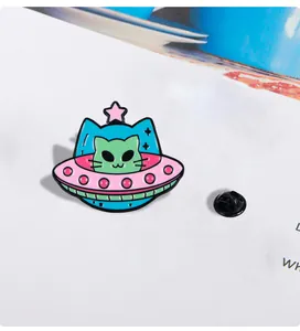 Macro detail of cartoon alien cat enamel pin with UFO design and black rubber clutch