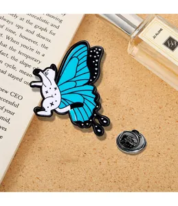Dettaglio di una spilla smaltata creativa gatto farfalla blu su sfondo di libri