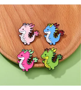 Set of four cartoon dragon brooches with pitaya fruit textures on a wooden tray