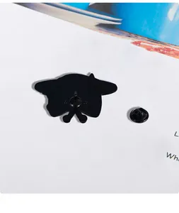 Detail view of metal cat badge back featuring black butterfly clasp and spur pin fastener