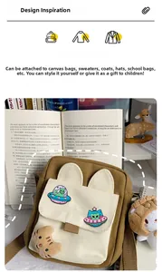 Detail of cute cat UFO enamel pins and plush kitten pendant on canvas shoulder bag