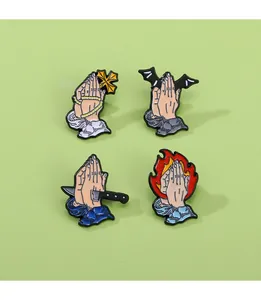 Detailed macro view of four enamel praying hand pins with cross, bat wings and fire motifs