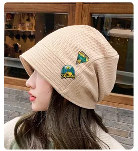 Dettaglio delle toppe ricamate su un berretto in maglia beige a coste sottili