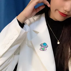 Detail shot of a cartoon UFO cat enamel pin on white suit lapel with star motifs