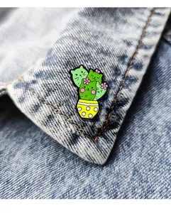 Detailaufnahme der süßen Kaktus-Katze Emaille-Anstecknadel an einer Jeansjacke