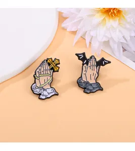 Detailed close-up of enamel prayer hand pins with cross and gothic bat wing motifs