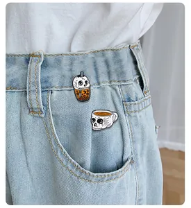 Close-up of skeleton boba and coffee pins worn on light blue denim jeans pockets