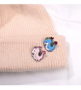 Close-up of pink and blue enamel dragon pins decorated on a knitted beanie hat