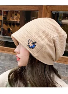 Detail of apricot knit beanie with a colorful street-style praying hands embroidery
