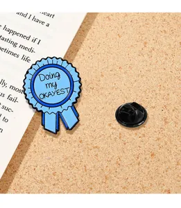 Détail de la broche médaille en émail bleu avec texte Doing my OKAYEST et fermoir