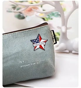 Macro shot of 4th of July star enamel pin on a denim zipper pouch with accessories