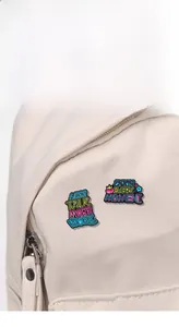Macro shot of colorful enamel pins with motivational quotes on a canvas backpack