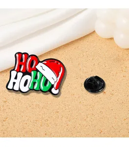 Dettaglio della spilla natalizia smaltata con scritta HO HO HO e design del cappello