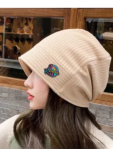 Profile view of a cream-colored ribbed knit beanie worn by a model in a street setting