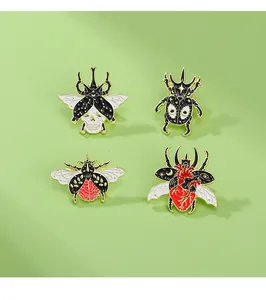 Detail of four gothic beetle enamel pins with skull and heart patterns on green background