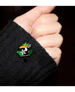 Détail de la broche toucan en émail avec feuilles vertes sur une manche noire