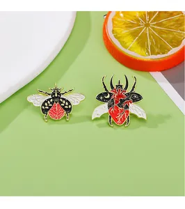Detail of bee and beetle brooches with anatomical heart design in enamel finish