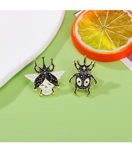 Close-up of enamel beetle and skull brooches with gold metal edges on green background