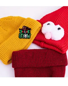 Dettaglio di cappelli in maglia con spilla Let it Snow e decorazioni a forma di occhi