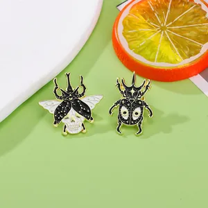 Gothic skull beetle and horned beetle enamel pins in black, gold, and white finish