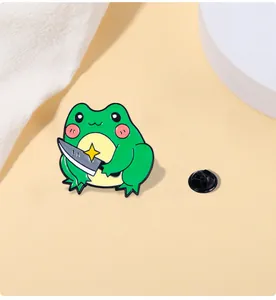 Detail shot of cute green frog enamel pin holding a knife with black rubber clutch back