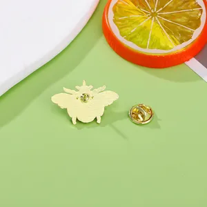 Golden bee insect brooch back view with butterfly clasp on a green background