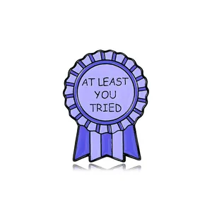 Purple award ribbon enamel pin featuring At Least You Tried quote on white background